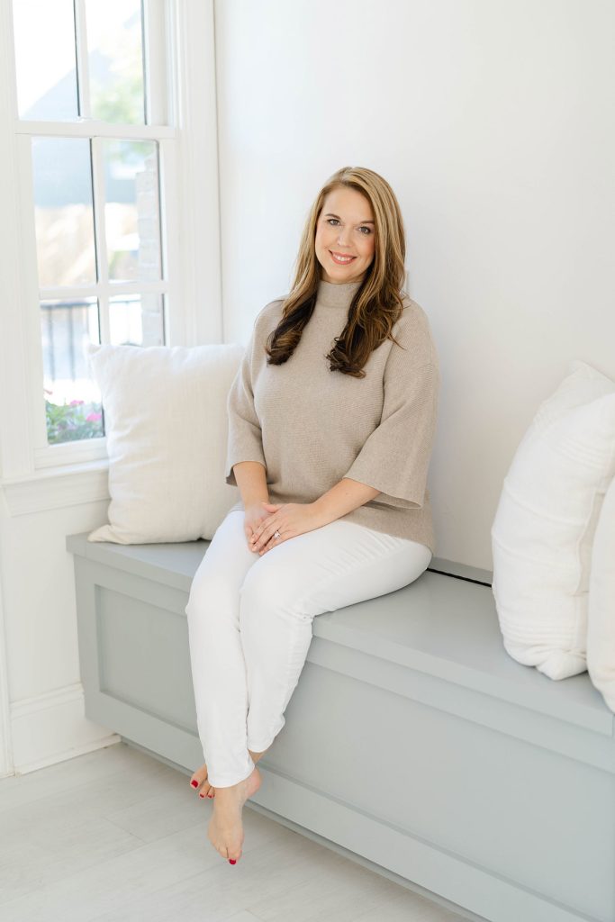 Cortney Sparkman sitting on a Hunter Green Sofa with white pillows