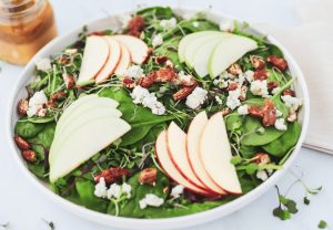 Spinach salad with sliced apples, walnuts and blue cheese crumbles with a side of vinaigrette
