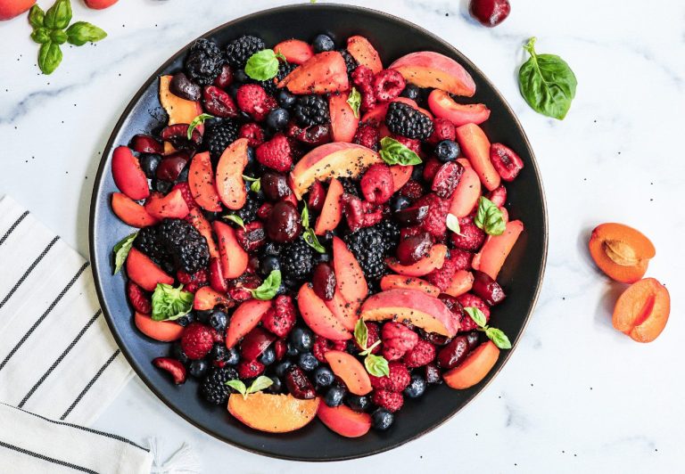 A colorful plate of stone fruits including raspberries, peaches, nectarines and plums