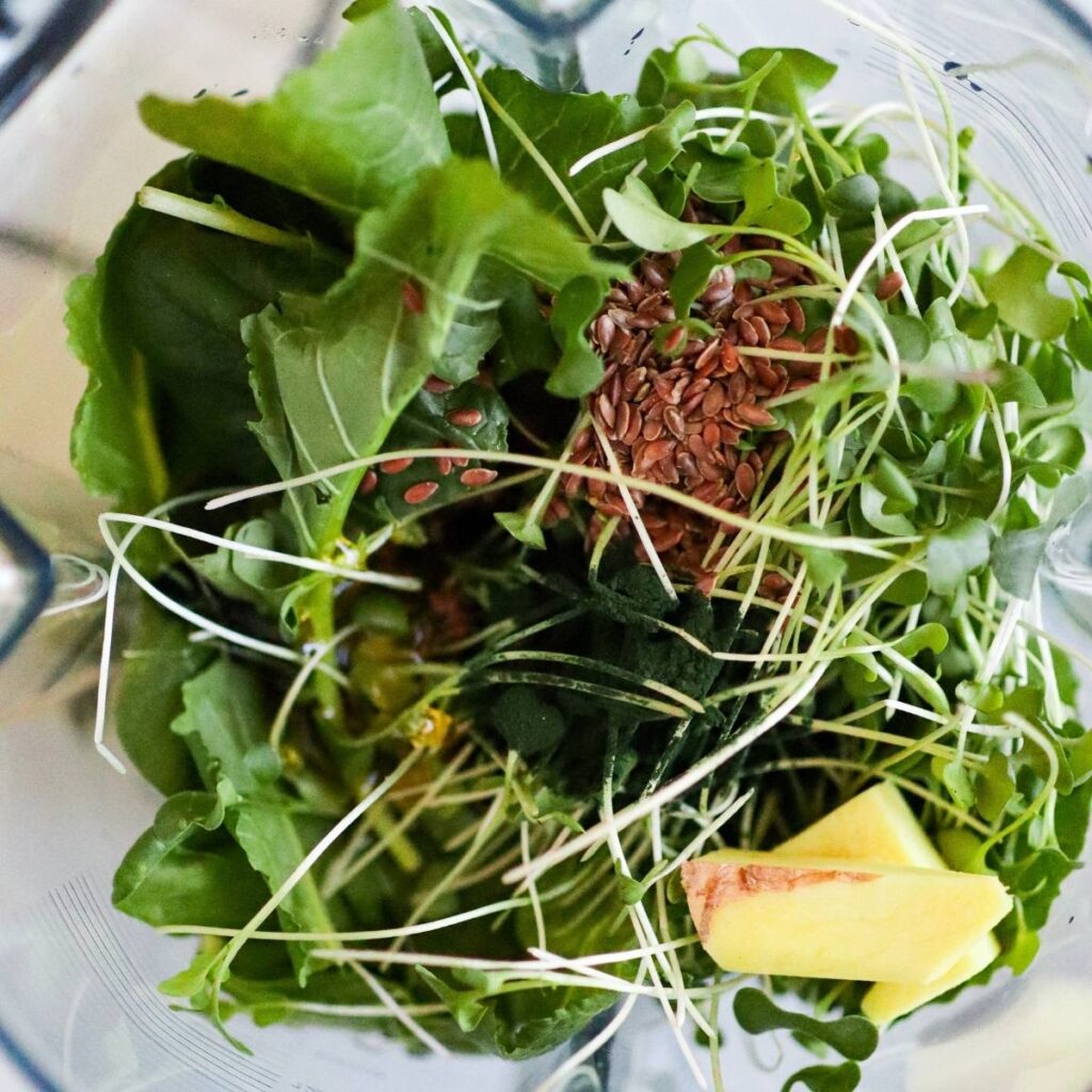 A small knob of fresh ginger, flaxseed and spirulina being added to the blender.